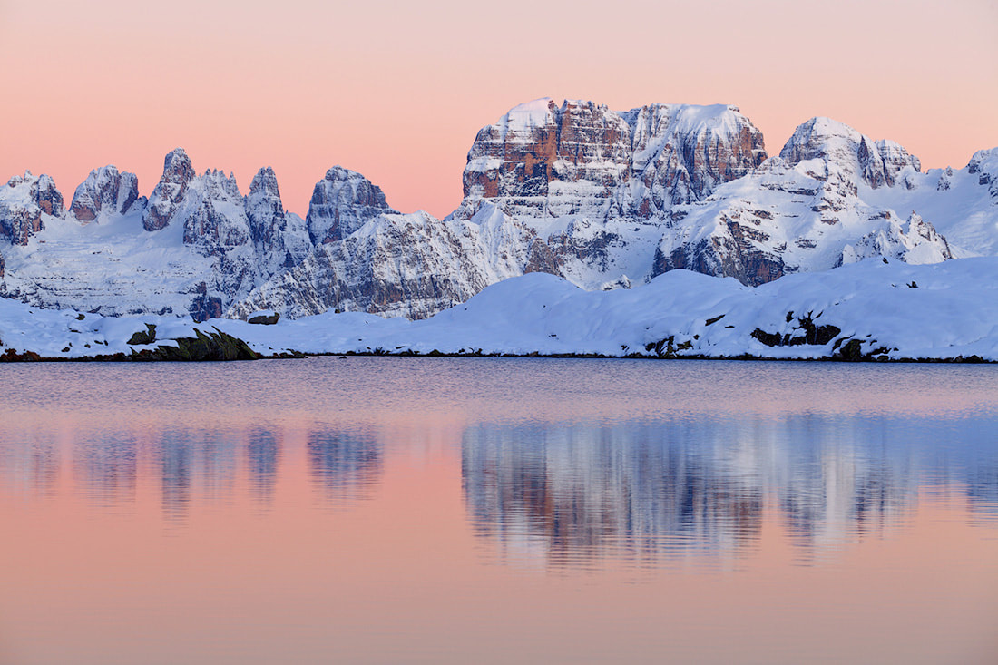 Le Dolomiti di Brenta, imbiancate dalla neve, si specchiano nelle acque del lago Nero di Cornisello, in alta val Nambrone